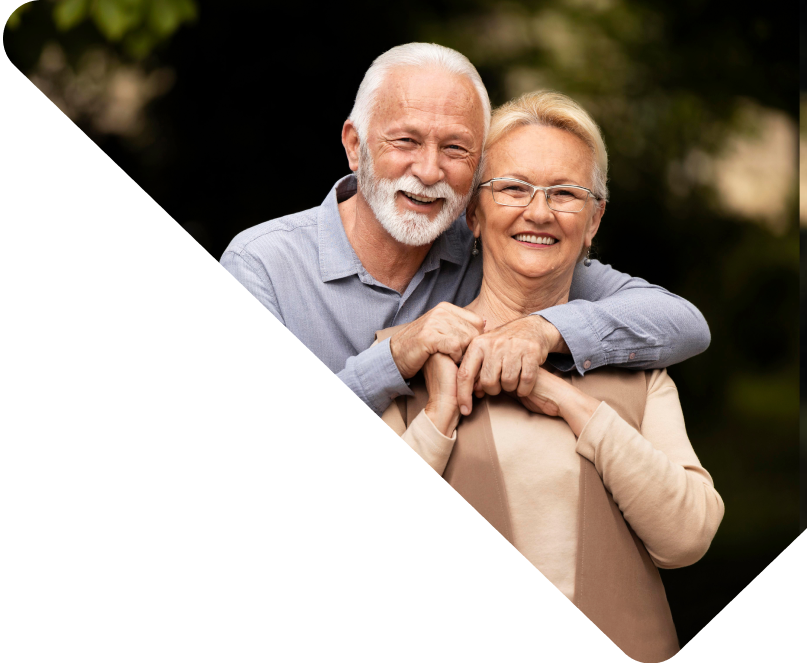 Um senhor e uma senhora abraçados e sorrindo.