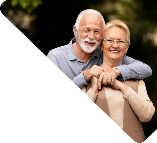 Um senhor e uma senhora abraçados e sorrindo.