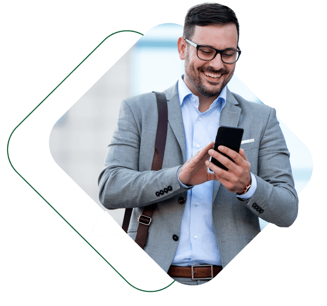 Homem de terno cinza segurando um celular e sorrindo.